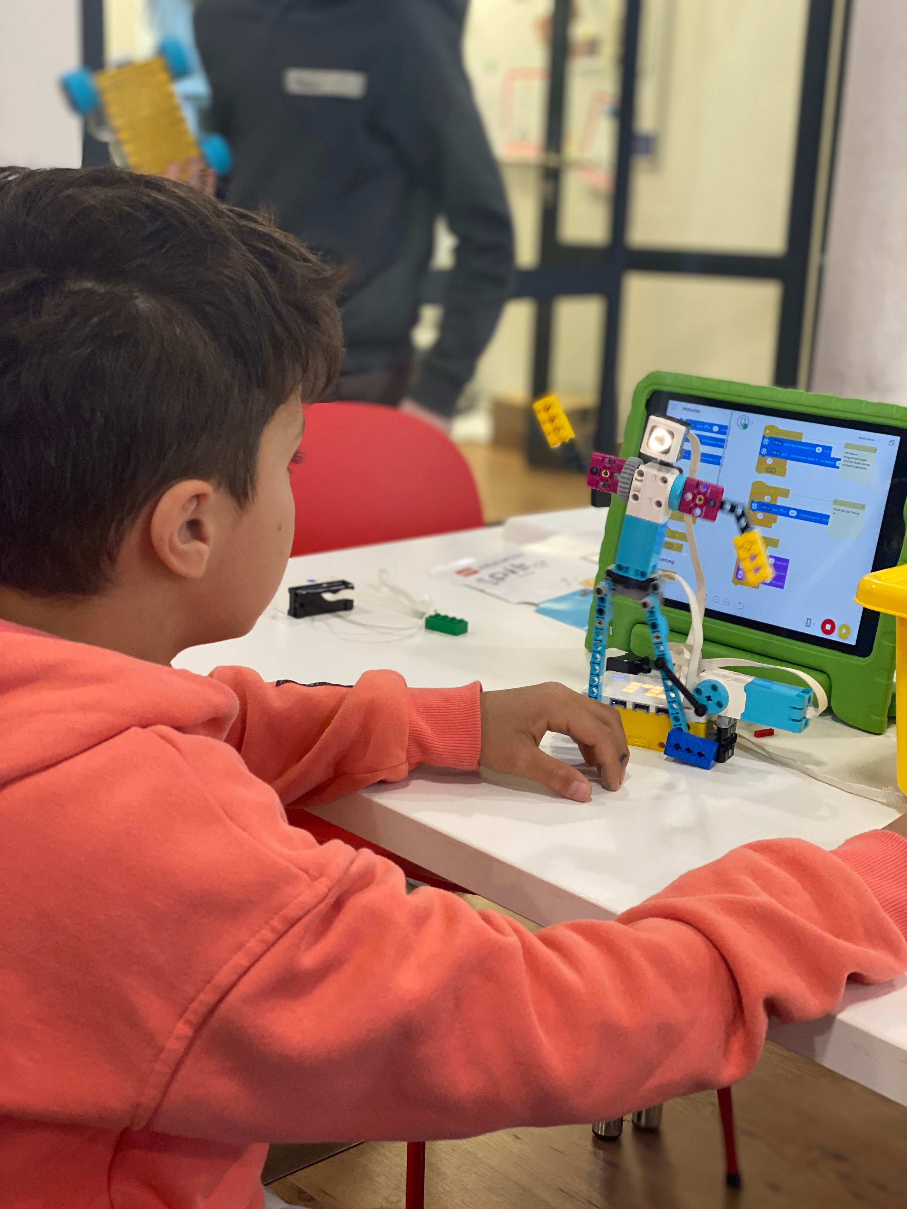Ein Junge bastelt und programmiert mit Lego Spike einen Tanzroboter